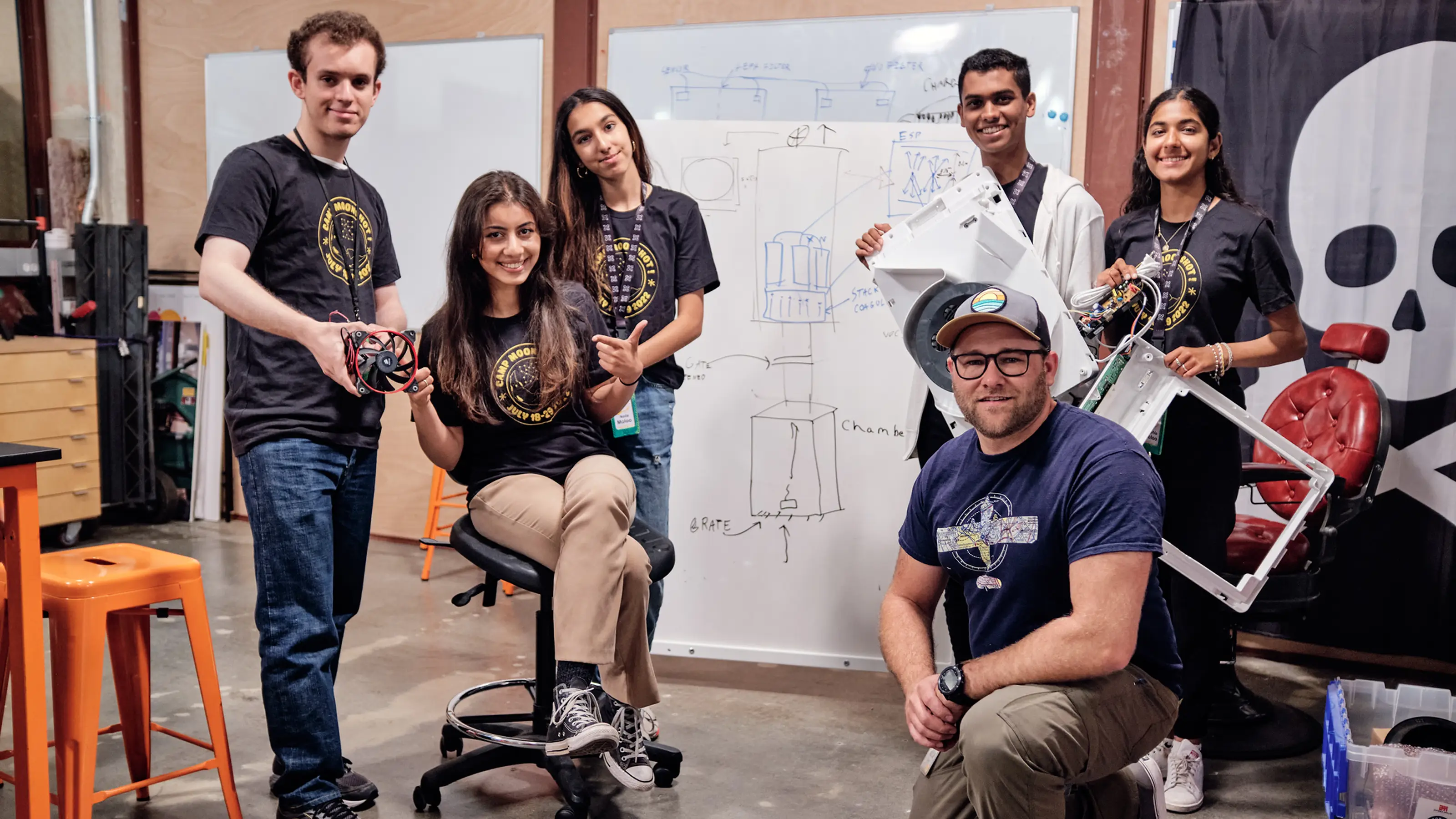 A TKS team working at a whiteboard with hardware during a moonshot project
